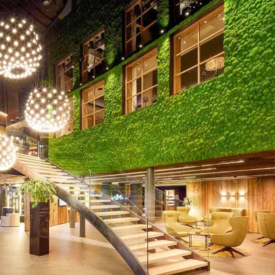 Hotel atrium with preserved moss walls rising across several levels beside a curved staircase