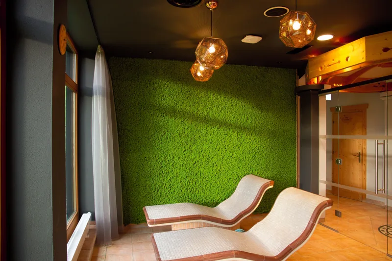 Wellness relaxation room with two loungers facing a bright green preserved moss wall