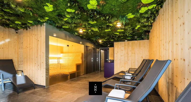 Sauna landscape with a preserved moss ceiling of mixed green foliage above wooden loungers